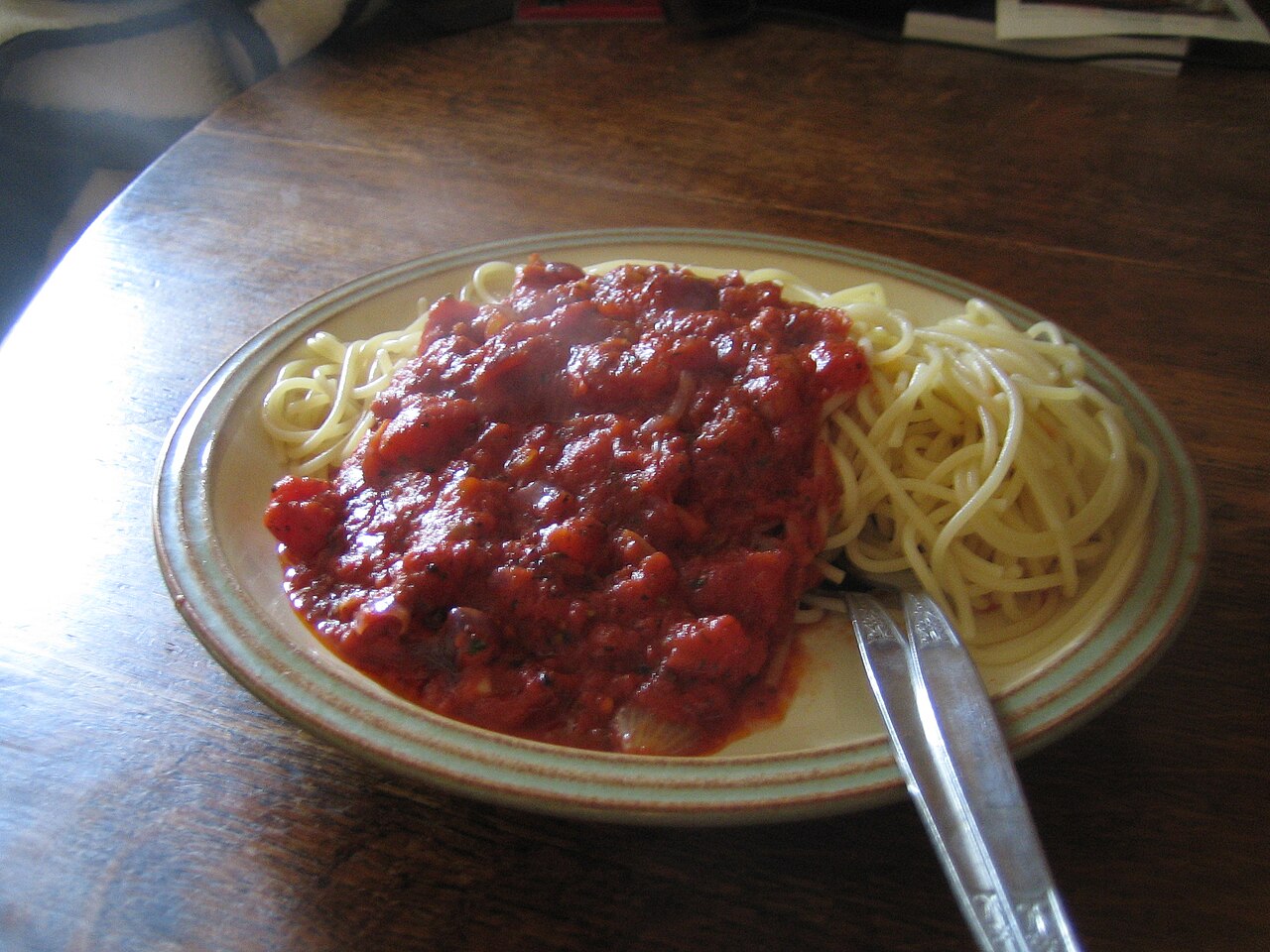 Bowl of pasta puttanesca with olives, capers, and tomato sauce