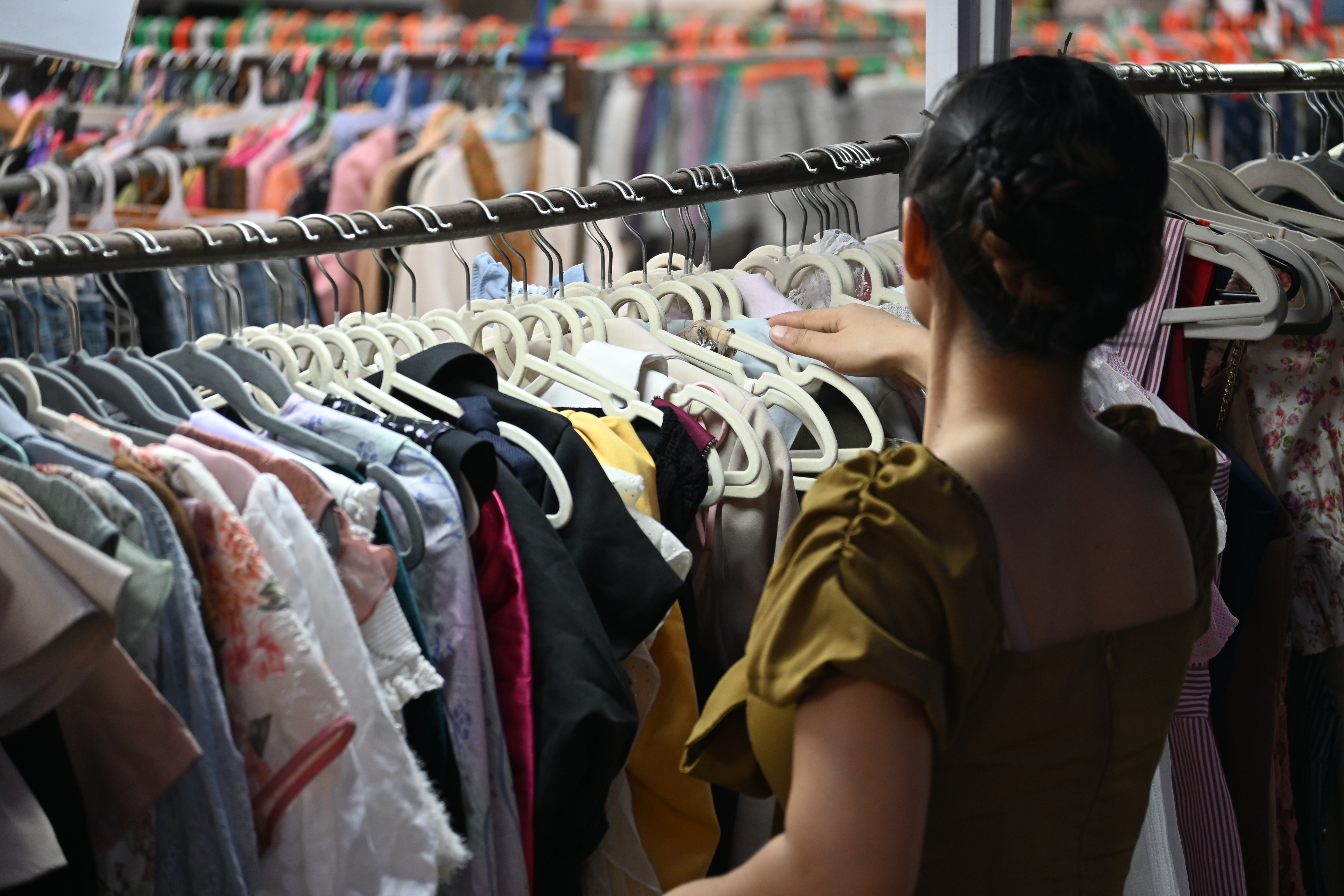 Colourful clothing hanging on racks at a secondhand thrift store